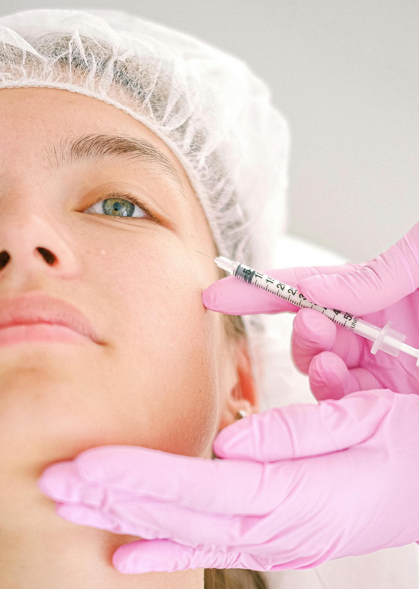 Close-up of a beautician administering facial injection treatment to a woman in a clinical setting.