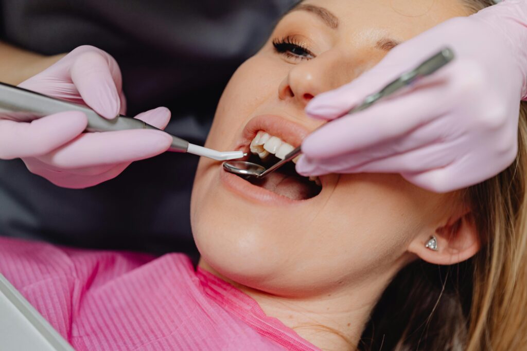 Close-up of a woman receiving dental care with a dentist using tools inside a clinic.