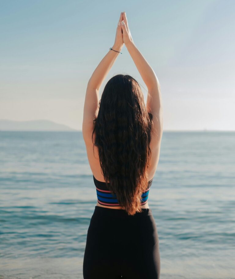 Woman meditating on the beach, embracing serenity and balance with an ocean view.